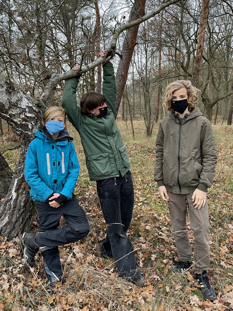 Drei Personen mit Schutzmasken im Wald